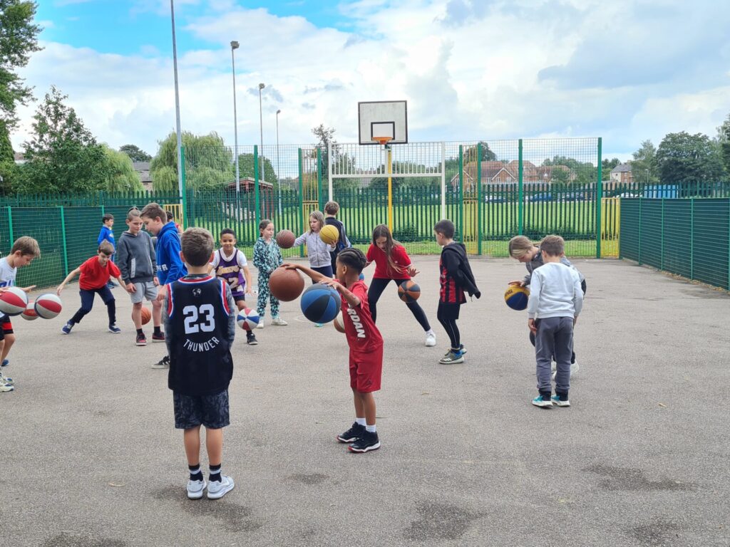 Image shows children playing a game of basketball